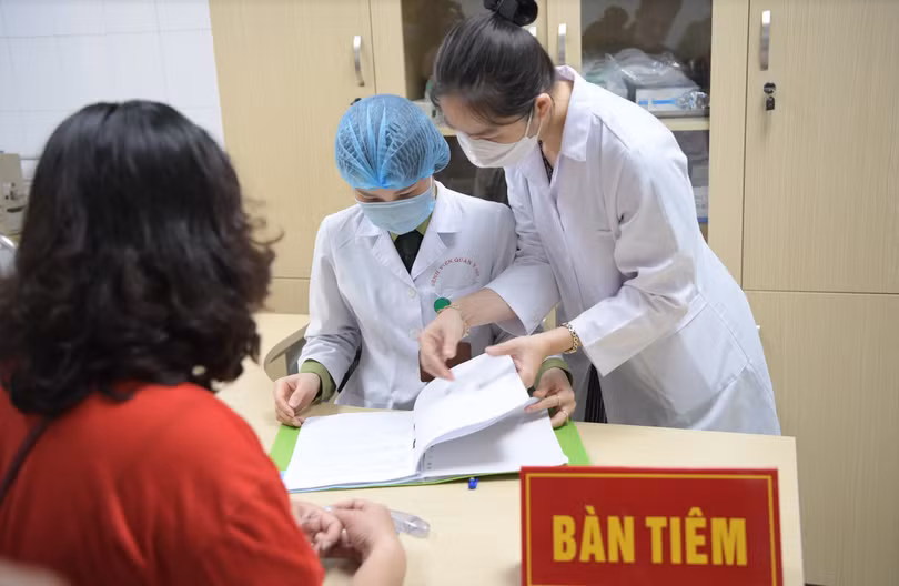 Tại bàn tiêm, các nhân viên y tế xem xét hồ sơ của tình nguyện viên