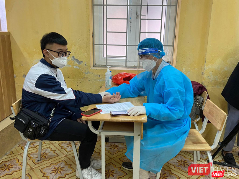 Nhân viên y tế kiểm tra sức khoẻ học sinh trước khi tiêm vaccine COVID-19 (Ảnh - Quang Hùng)