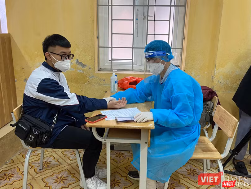 Nhân viên y tế kiểm tra sức khoẻ học sinh trước khi tiêm vaccine COVID-19 (Ảnh - Quang Hùng)