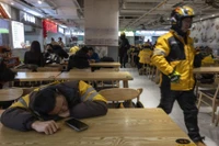 Một nhân viên giao hàng ở Trung Quốc tranh thủ nghỉ ngơi sau giờ cao điểm ăn trưa. Ảnh: WSJ.