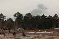 Người dân đang làm việc trong quá trình mở rộng nghĩa trang, trong khi khói bốc lên sau các cuộc không kích phía sau nghĩa trang Behesht-e Zahra ở Tehran, Iran ngày 16/3. Ảnh: Reuters.