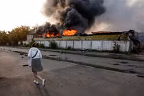 Một người qua đường đi bộ gần một tòa nhà đang bốc cháy tại địa điểm xảy ra cuộc tấn công bằng máy bay không người lái của Nga nhằm vào Kiev hôm 10/6. Ảnh: Reuters.