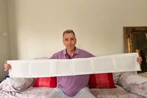 Laurence Watkins, một nhân viên bảo vệ đã nghỉ hưu đến từ Auckland, New Zealand, cầm trên tay giấy khai sinh dài 6 trang, trong đó ghi đầy đủ 2.253 cái tên của ông. Ảnh: CNN.