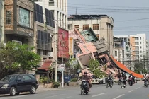 Người dân đi xe máy qua một tòa nhà bị đổ sập sau trận động đất ở Mandalay, Myanmar hôm 28/3. Ảnh: Reuters.