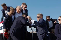 Cựu Tổng thống Donald Trump được các nhân viên Sở Mật vụ bảo vệ ra khỏi sân khấu (Ảnh: Getty)