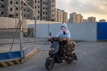 Một người phụ nữ đi ngang qua dự án phát triển nhà ở chưa hoàn thiện của Evergrande (Ảnh: Bloomberg)