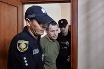 Các sĩ quan cảnh sát áp giải nghi phạm trong vụ sát hại nhà lập pháp Ukraine Andriy Parubiy vào phòng xử án ở Lviv, Ukraine, ngày 2/9. Ảnh: Reuters.