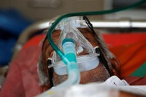 Một bệnh nhân được cho thở bình oxy trong xe cấp cứu, chờ được nhập viện điều trị COVID-19 (Ảnh: Reuters)