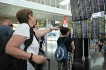 Hành khách nhìn vào màn hình hiển thị các chuyến bay bị trì hoãn tại sân bay Barcelona vào ngày 19/7, ở Barcelona, ​​​​Tây Ban Nha (Ảnh: Getty)