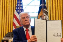 Tổng thống Mỹ Donald Trump cầm một lệnh hành pháp đã ký về tại Phòng Bầu dục ở Nhà Trắng ở Washington, D.C., Mỹ ngày 9/4. Ảnh: Reuters.