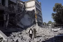 Người dân đi bộ giữa đống đổ nát sau cuộc không kích mạnh mẽ của Israel làm rung chuyển Damascus vào ngày 16/7. Ảnh: Reuters.