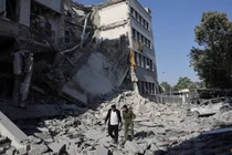 Người dân đi bộ giữa đống đổ nát sau cuộc không kích mạnh mẽ của Israel làm rung chuyển Damascus vào ngày 16/7. Ảnh: Reuters.