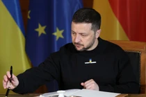 Tổng thống Ukraine Volodymyr Zelensky đang ký vào một cuốn sổ lưu bút. Ảnh: Getty.