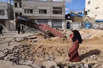 Một người phụ nữ đi bộ qua một con đường bị phá hủy sau cuộc không kích của Israel tại Khan Younis ở phía nam Dải Gaza vào ngày 14/5. Ảnh: AFP.