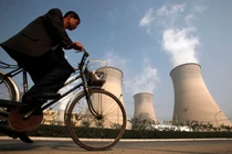 Một người đàn ông đạp xe qua ống khói của một nhà máy điện nằm ở ngoại ô Bắc Kinh vào ngày 29/10/2009. Ảnh: Reuters.