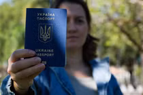 Bà Kateryna Golizdra cầm hộ chiếu Ukraine của mình để chụp ảnh bên ngoài nhà mình ở Margate, Florida, Mỹ ngày 17/11. Ảnh: Reuters.
