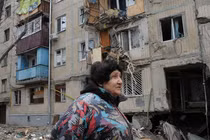 Một người phụ nữ đi qua tòa nhà bị hư hại do pháo kích ở Kharkiv, Ukraine (Ảnh: AP)