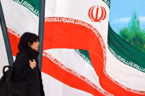 Một người phụ nữ đi ngang qua bức tranh tường vẽ cờ Iran ở Tehran. Truyền hình nhà nước Iran đã cố nói giảm về tác động của đòn tấn công của Israel (Ảnh: AFP)