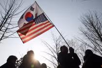 Một người cầm cờ Hàn Quốc và cờ Mỹ ở Uiwang, Hàn Quốc vào ngày 8/3. Ảnh: Reuters.