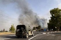 Một chiếc xe jeep của quân đội Israel đậu gần trạm kiểm soát khi khói bốc lên từ đám cháy do tên lửa phóng từ miền nam Lebanon, ở Thượng Galilee, Israel ngày 4/7/2024 (Ảnh: AFP)