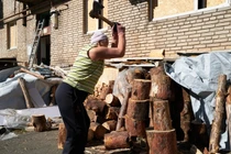 Một phụ nữ Ukraine chặt củi bên ngoài căn hộ của mình (Ảnh: Getty)