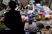 Một khách hàng đang xem hải sản tại một cửa hàng ở Tokyo, Nhật Bản ngày 19/11. Ảnh: Reuters.