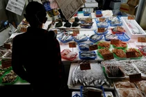 Một khách hàng đang xem hải sản tại một cửa hàng ở Tokyo, Nhật Bản ngày 19/11. Ảnh: Reuters.