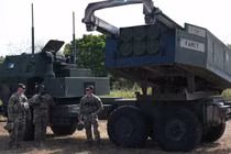 Các binh sĩ quân đội Mỹ đứng cạnh bệ phóng của hệ thống pháo phản lực cơ động cao (HIMARS) (Ảnh: AFP)