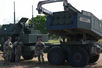 Các binh sĩ quân đội Mỹ đứng cạnh bệ phóng của hệ thống pháo phản lực cơ động cao (HIMARS) (Ảnh: AFP)