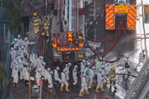 Cảnh sát mặc đồ bảo hộ đi bộ gần hiện trường vụ cháy chung cư tại khu nhà ở Wang Fuk Court sau vụ hỏa hoạn chết người ở Tai Po, Hong Kong, Trung Quốc, ngày 29/11. Ảnh: Reuters.