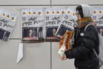 Một người phụ nữ đi ngang qua các tấm áp phích in hình Tổng thống Hàn Quốc Yoon Suk Yeol với dòng chữ "Tội phạm nổi dậy Yoon đã kết thúc" tại một ga tàu điện ngầm ở Seoul vào ngày 9/12. Ảnh: AFP.