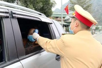 Công an TP Cẩm Phả vừa điều tiết giao thông vừa kết hợp với đo nhiệt độ người tham gia giao thông. Ảnh: UBND tỉnh Quảng Ninh.