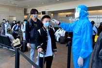 Nhân viên y tế kiểm tra nhiệt độ của hành khách ở sân bay (Ảnh - BYT) 