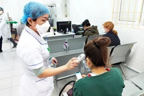 Nhân viên y tế đo nhiệt độ cho bệnh nhân (Ảnh - Minh Thuý) 