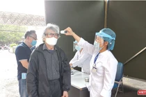 Nhân viên y tế kiểm tra nhiệt độ của người dân (Ảnh - Minh Thuý) 