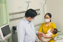 Bộ trưởng Bộ Y tế Nguyễn Thanh Long thăm em bé sau khi tiêm vaccine COVID-19 nhầm tại Trạm Y tế xã Yên Sơn, huyện Quốc Oai (Ảnh - Mạnh Cường) 