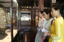 Du khách sử dụng smartphone với chip NFC gắn trên cổ vật trưng tại Cung đình Huế.