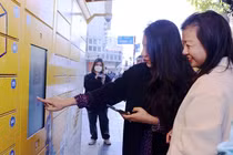 Người dân Hà Nội trải nghiệm trạm giao nhận thông minh bằng thao tác trên điện thoại và màn hình cảm ứng tại trạm.