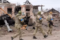 Quân đội Ukraine tái chiếm lại thị trấn Trostyanets hôm 26/3. Ảnh: những binh sĩ Ukraine đi ngang qua xác một chiếc xe tăng Nga giữa đống đổ nát (Ảnh: AP).