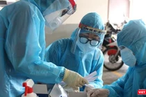 Lấy mẫu xét nghiệm trong vùng phong toả vì BN COVID-19 - Ảnh: HCDC