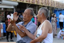 Hai người cao niên đang sử dụng điện thoại di động ở tỉnh Sơn Đông, tháng 5/2017. Ảnh: VCG.