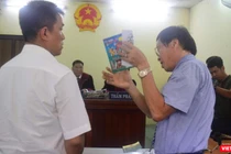 Họa sĩ Lê Linh (áo trắng) và ông Nguyễn Vân Nam (người đang cầm cuốn sách) - đại diện cho công ty Phan Thị với những trao đổi gay gắt tại tòa 