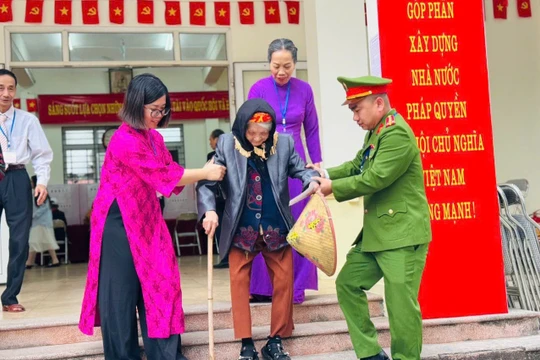 Cán bộ tổ bầu cử ở Hà Nội giúp cụ bà di chuyển sau khi bỏ phiếu. 
