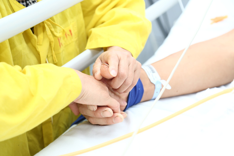 Chị Mính nắm chặt tay chồng trên giường bệnh. Ảnh: BVCC