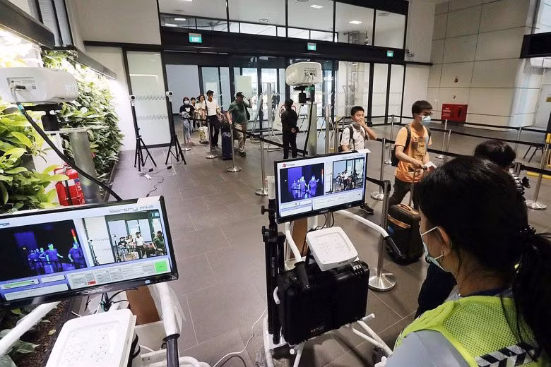 Nhân viên kiểm tra thân nhiệt tại sân bay. Ảnh: KELVIN CHNG