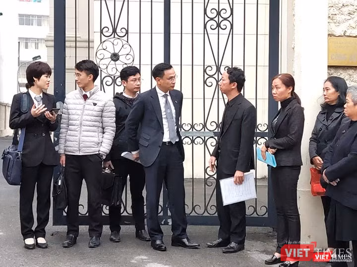 Bố cháu Long (người cầm tập giấy trắng) trao đổi cùng luật sư trước khi tham dự phiên tòa. Ảnh: Minh Thúy