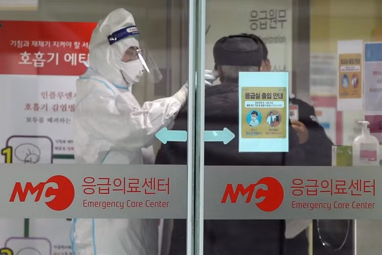 Nhân viên y tế kiểm tra nhiệt độ của bệnh nhân. Ảnh: EPA-EFE