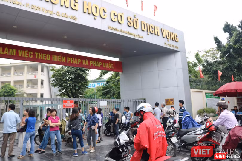 Nhiều phụ huynh đội mưa đưa con đi thi . Ảnh: Minh Thúy