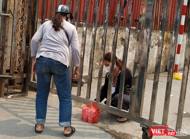 Việc tiếp tế đồ ăn tại cổng Bệnh viện Bạch Mai trên phố Phương Mai vẫn diễn ra trước sự chứng kiến của bảo vệ. Ảnh: Anh Lê.