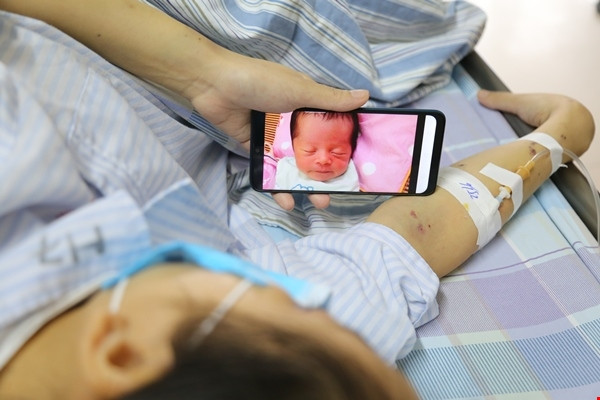 Chị Vang ngắn nhìn đứa con thơ qua màn hình điện thoại trong lúc điều trị.